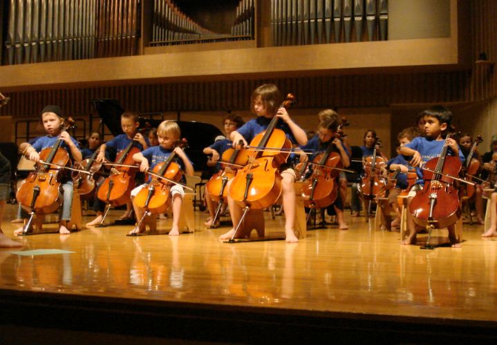 young children playing cellos
